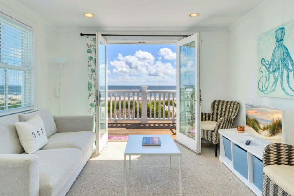 Light-filled living room with ocean view and patio doors opening to a beachfront balcony.